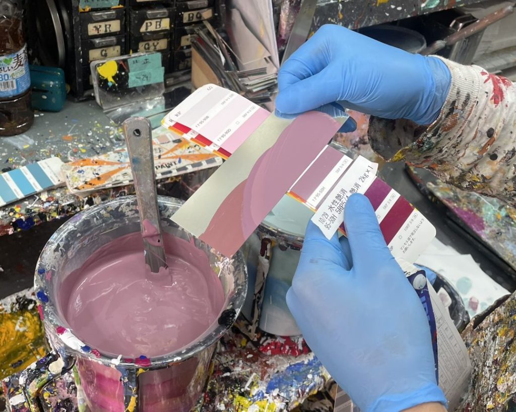 色見本(日塗工色見本帳)を使い、微妙な色の差を見比べながら調色している様子